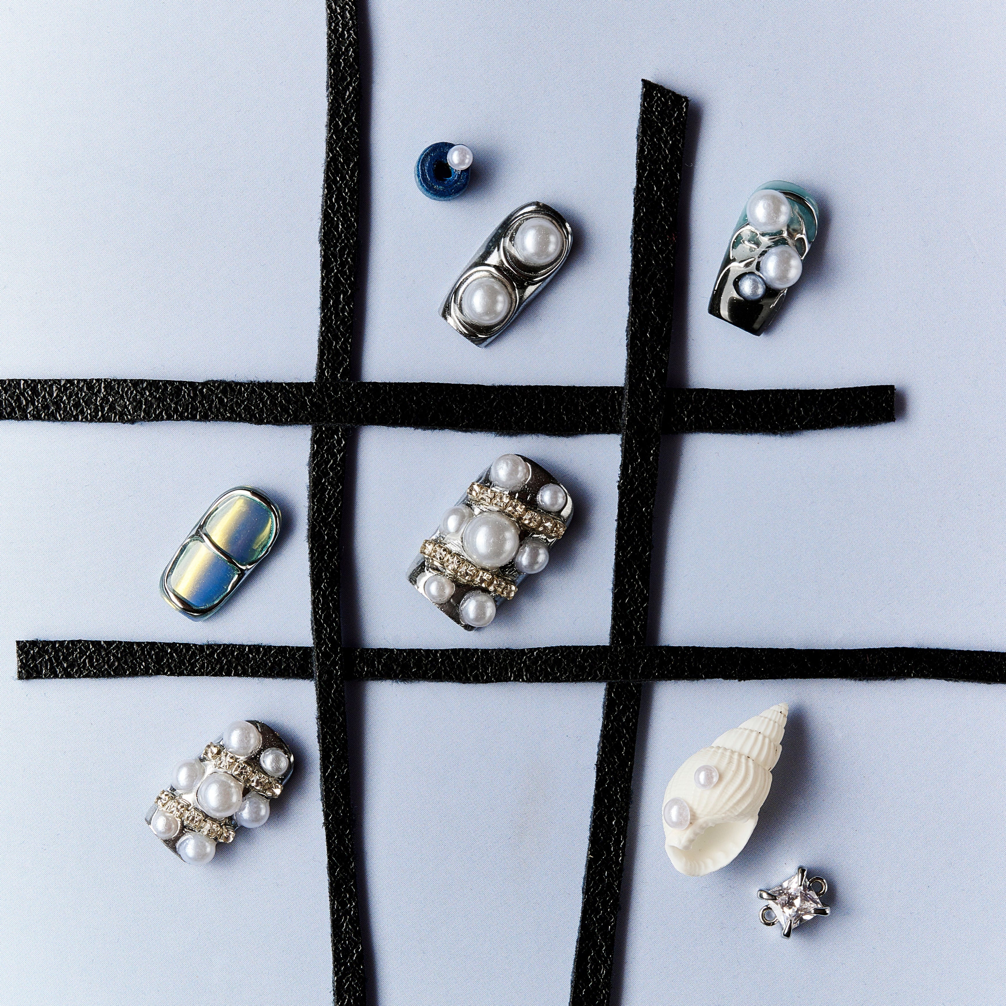 Cyber-style press on nails with chrome metallic finish, pearl embellishments and futuristic design.