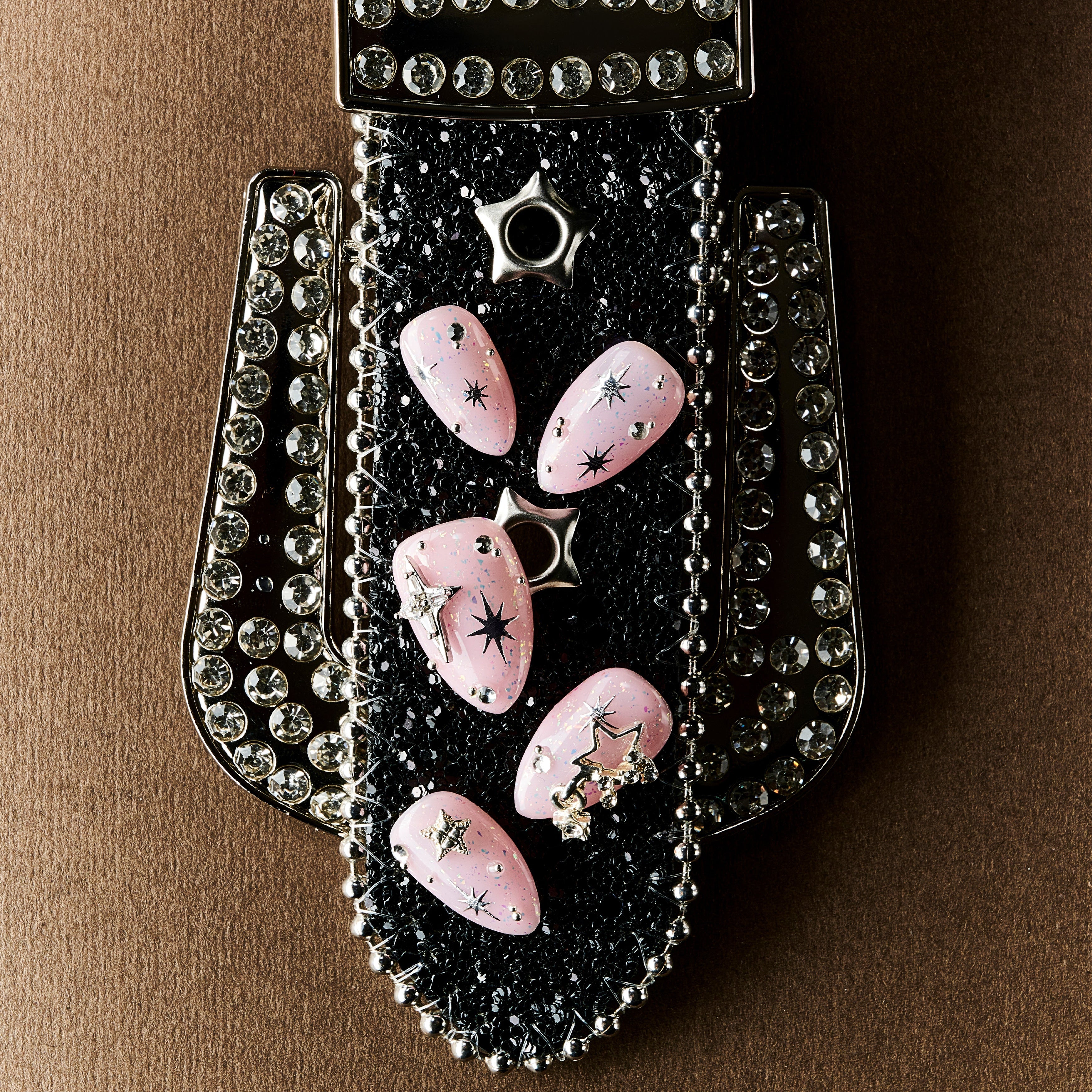 Dreamy pink glitter press on nails with star charms and crystal details. Soft glam and reusable.