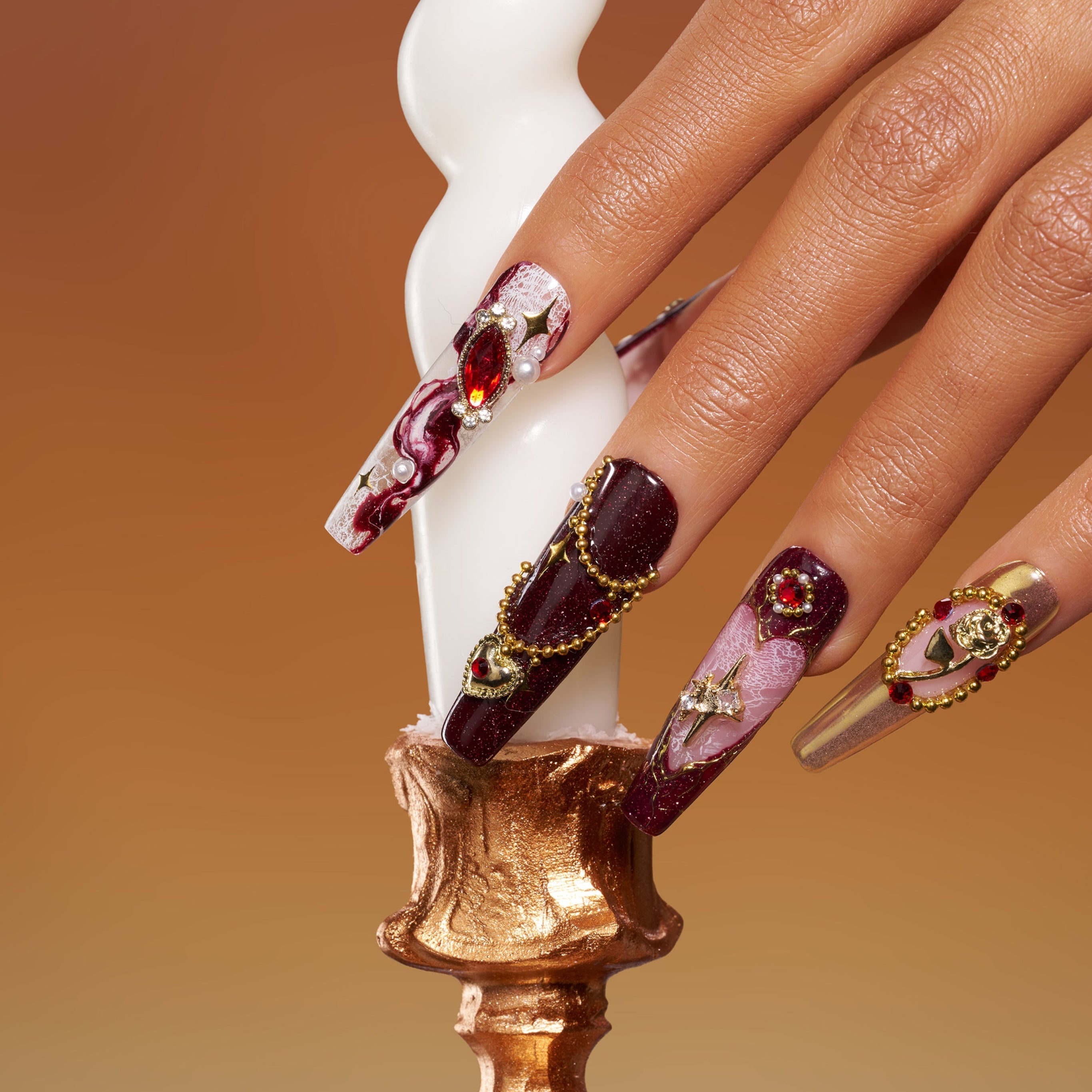 Burgundy press on nails with gold detailing and heart gemstone accents. Romantic, bold and reusable.