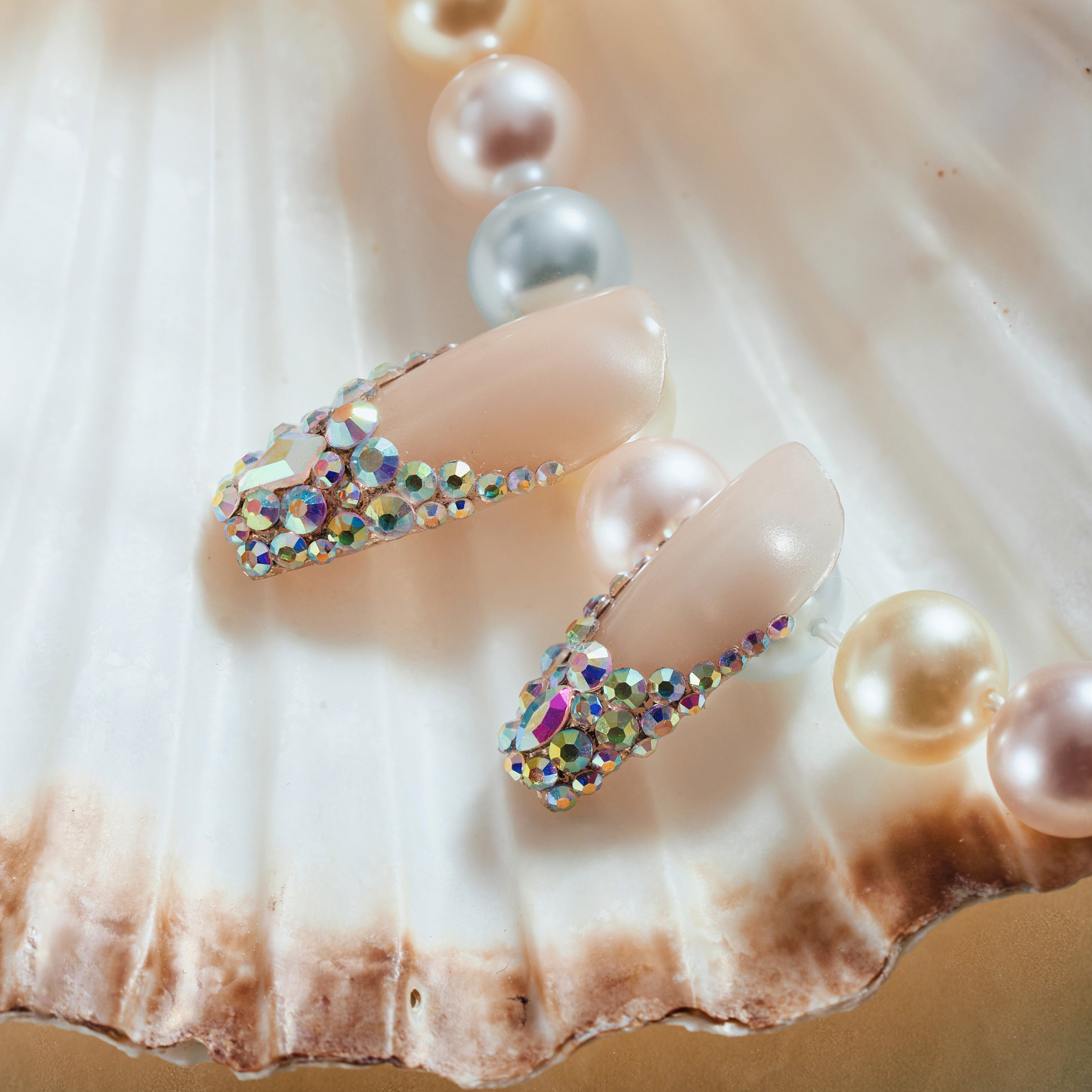 Luxury nude pink press on nails with oversized iridescent crystals and rhinestone detailing. Glamorous and reusable.