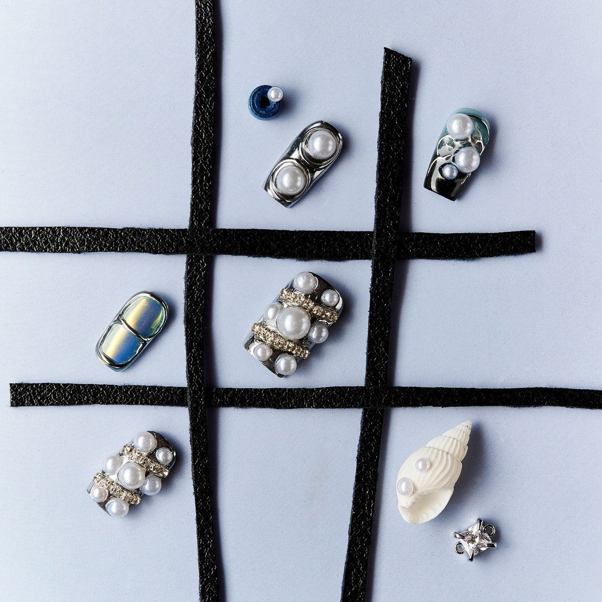 Cyber-style press on nails with chrome metallic finish, pearl embellishments and futuristic design.