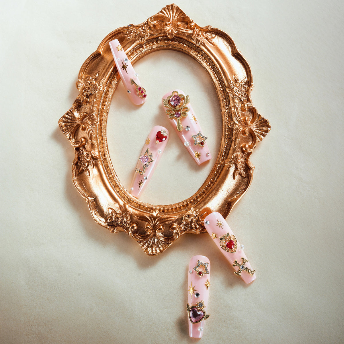 Princess Secret press on nails with gold charms, red gems, pearls, and glossy nude-pink base.