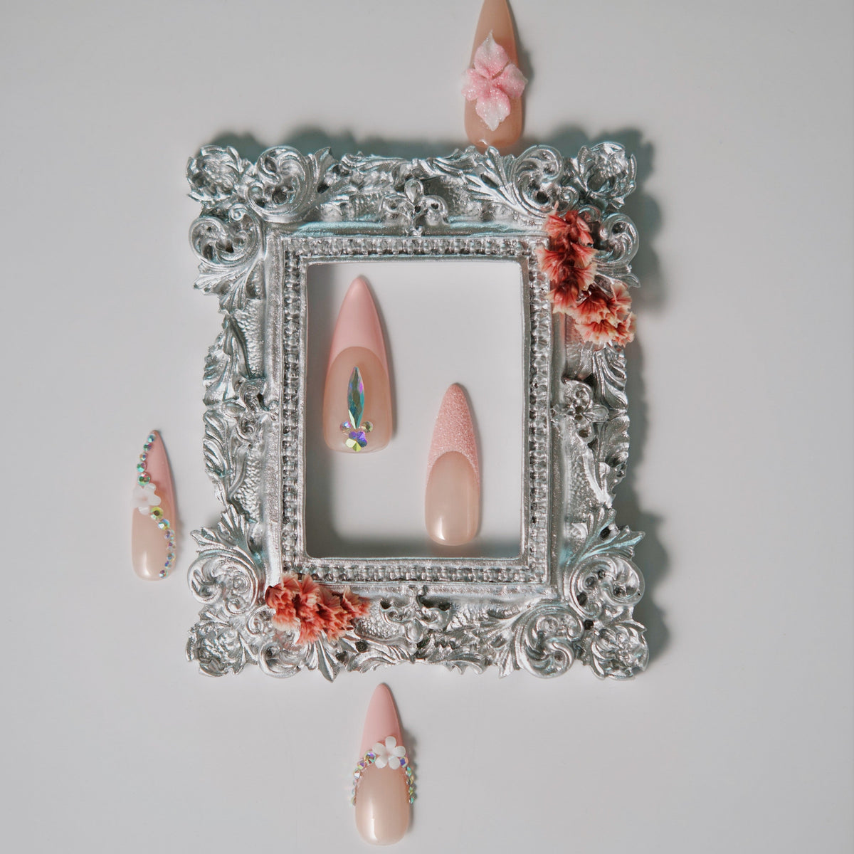 Nude press on nails with silver rhinestone arcs and floral accents. Elegant sparkle and reusable.