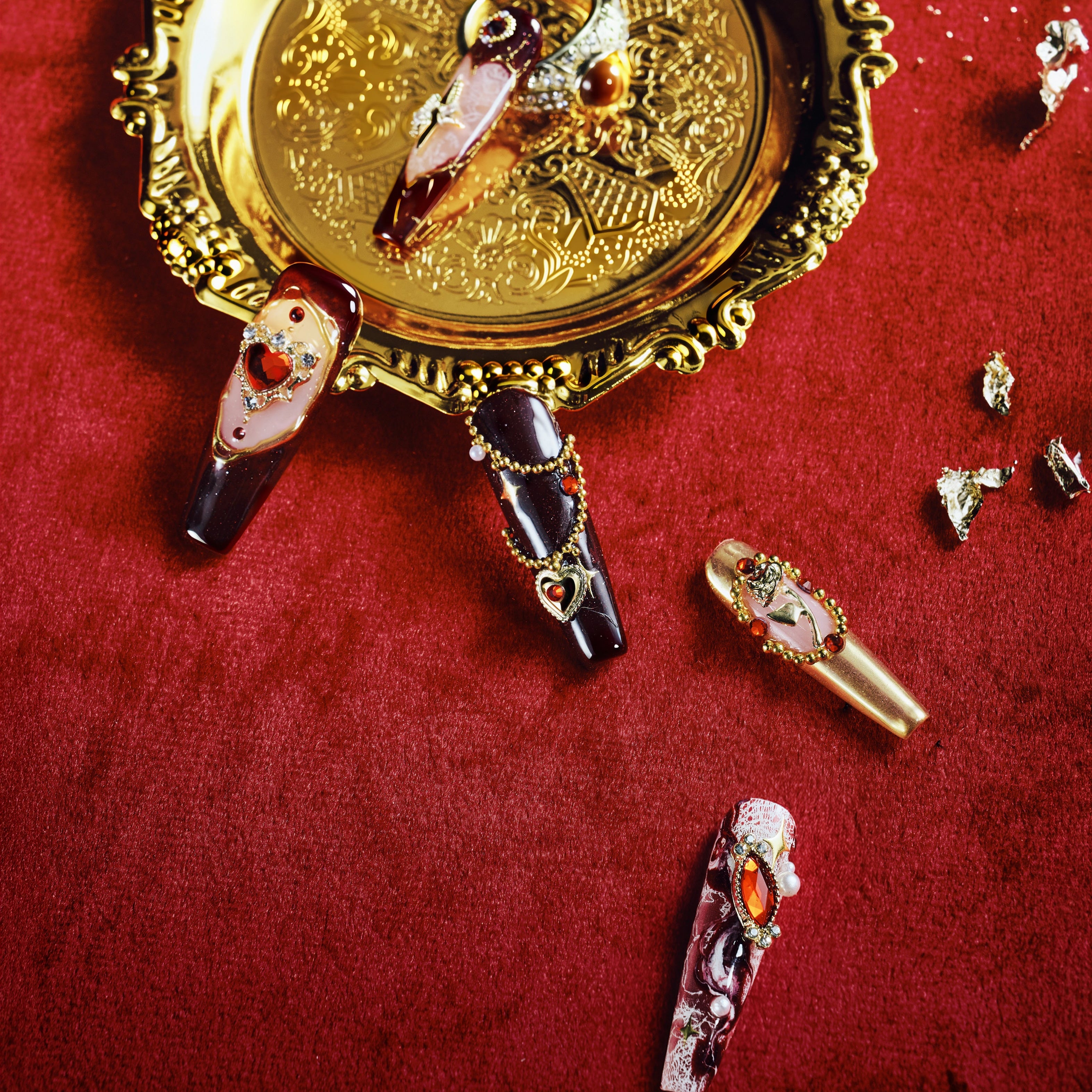 Burgundy press on nails with gold detailing and heart gemstone accents. Romantic, bold and reusable.