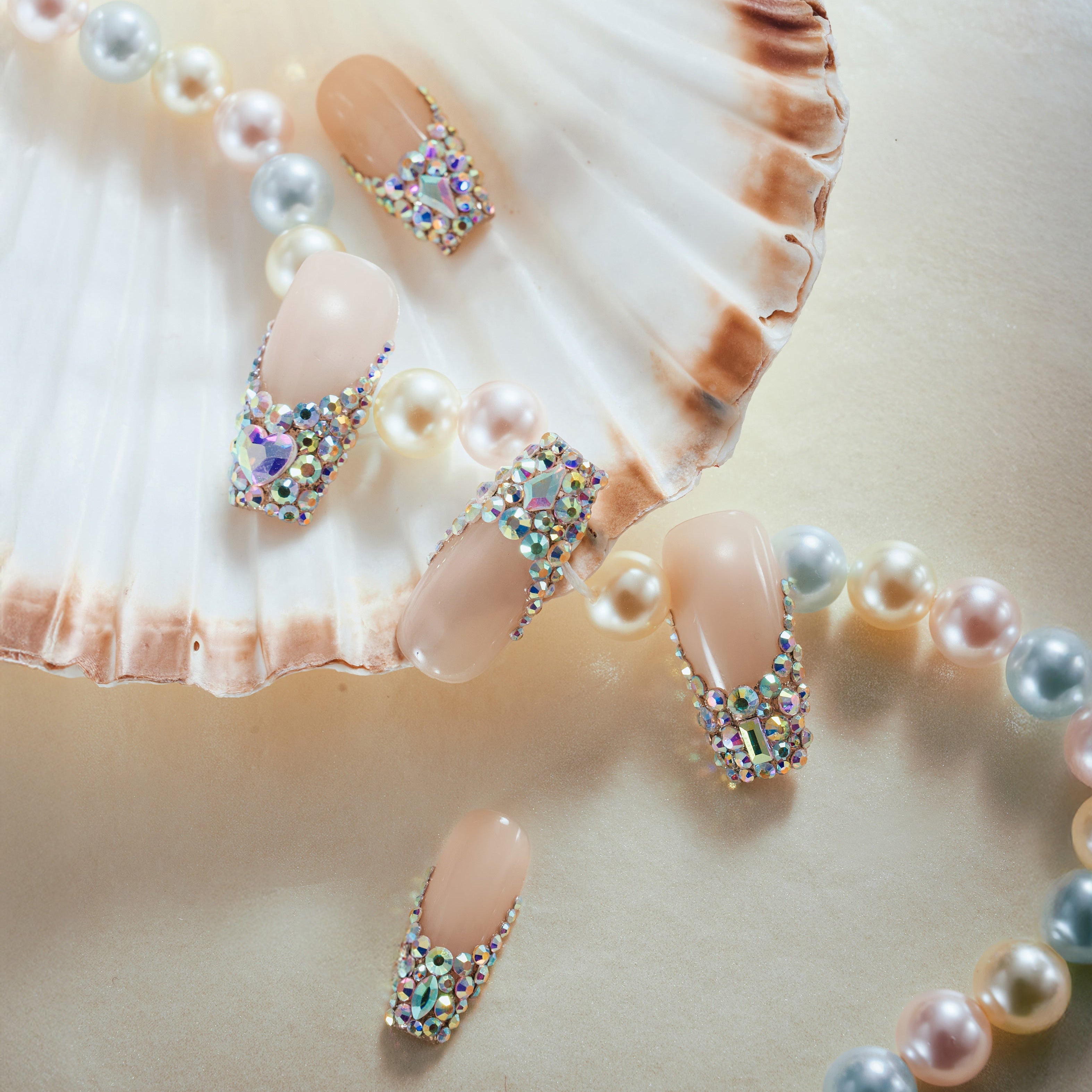 Luxury nude pink press on nails with oversized iridescent crystals and rhinestone detailing. Glamorous and reusable.