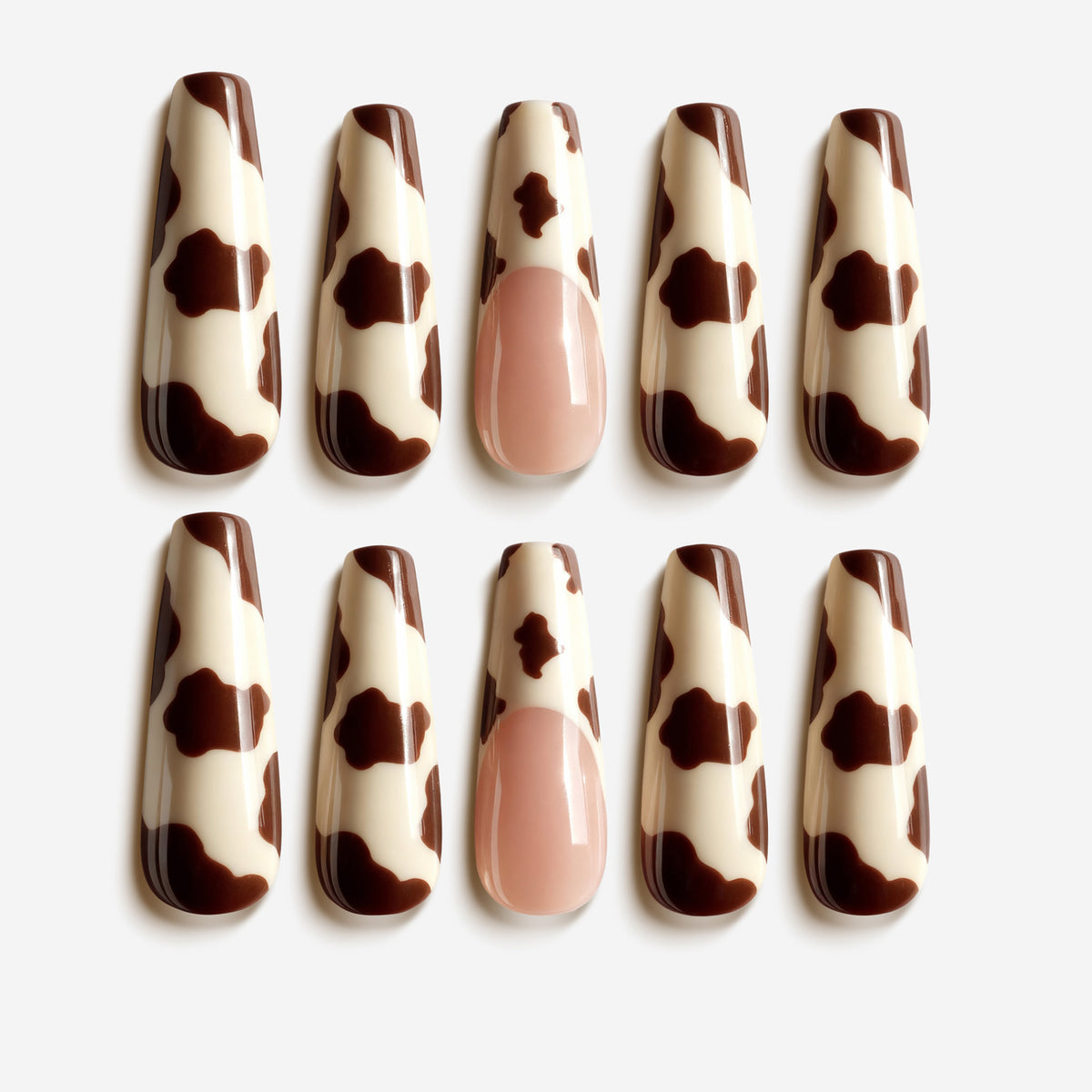 Mocha Pasture press on nails with brown cow-print pattern and nude accent nail
