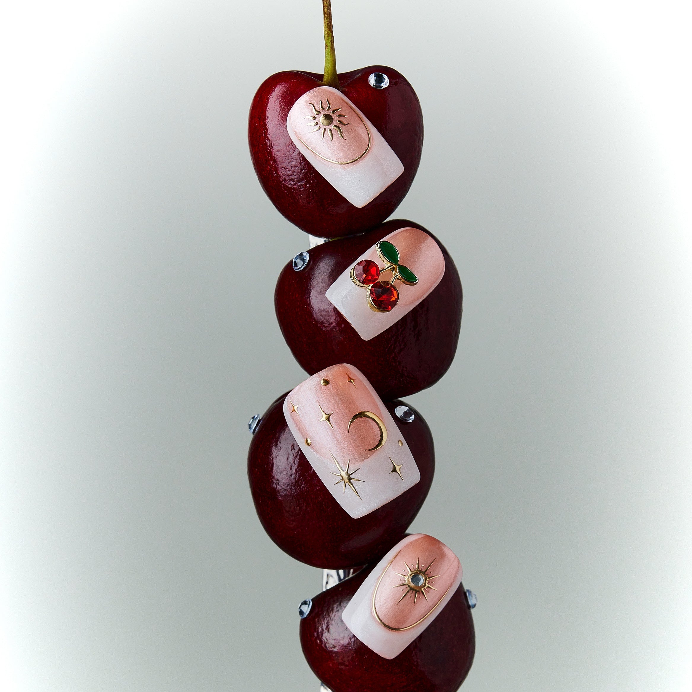 Starlit Cherry pink press on nails with gold accents and cherry details.