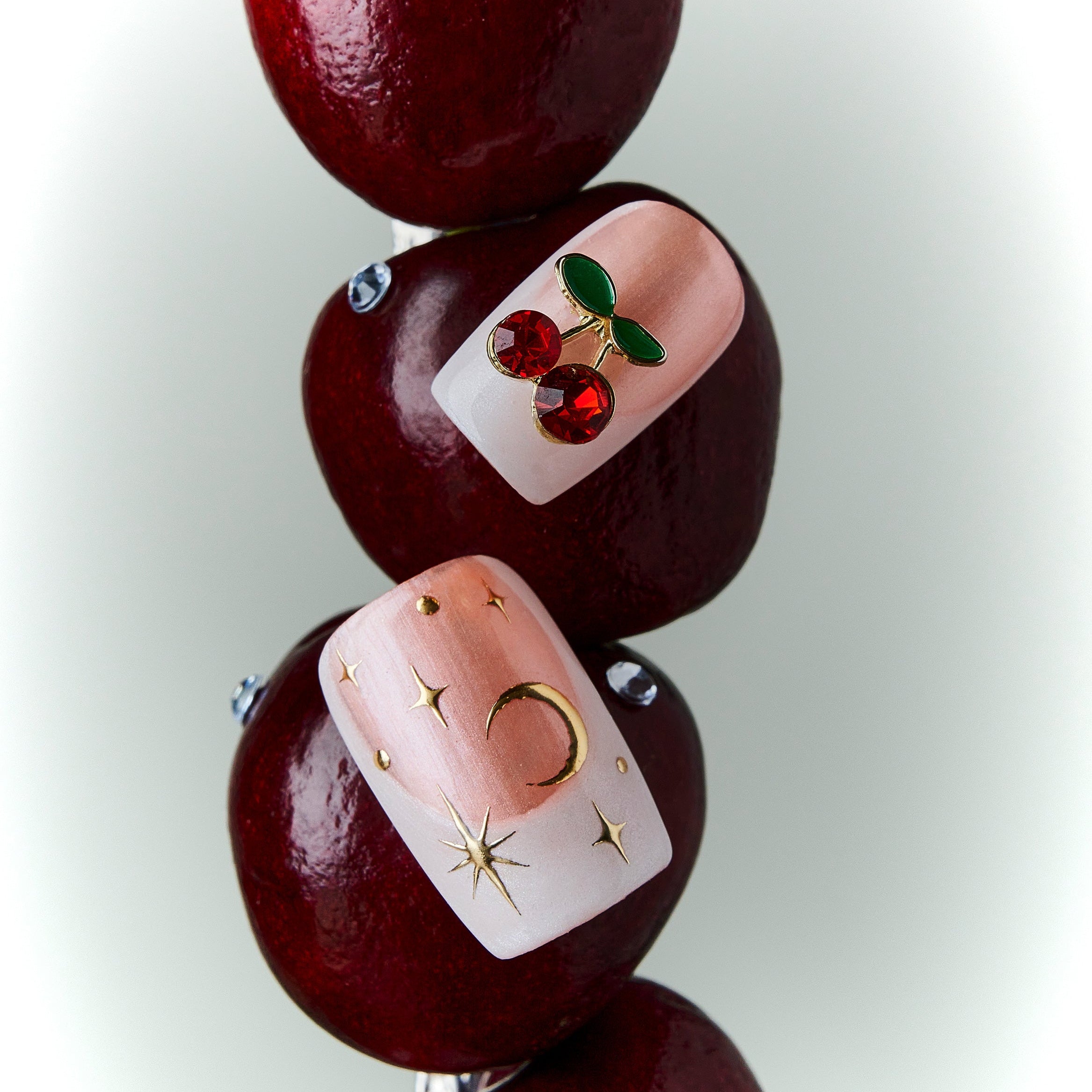 Starlit Cherry pink press on nails with gold accents and cherry details.