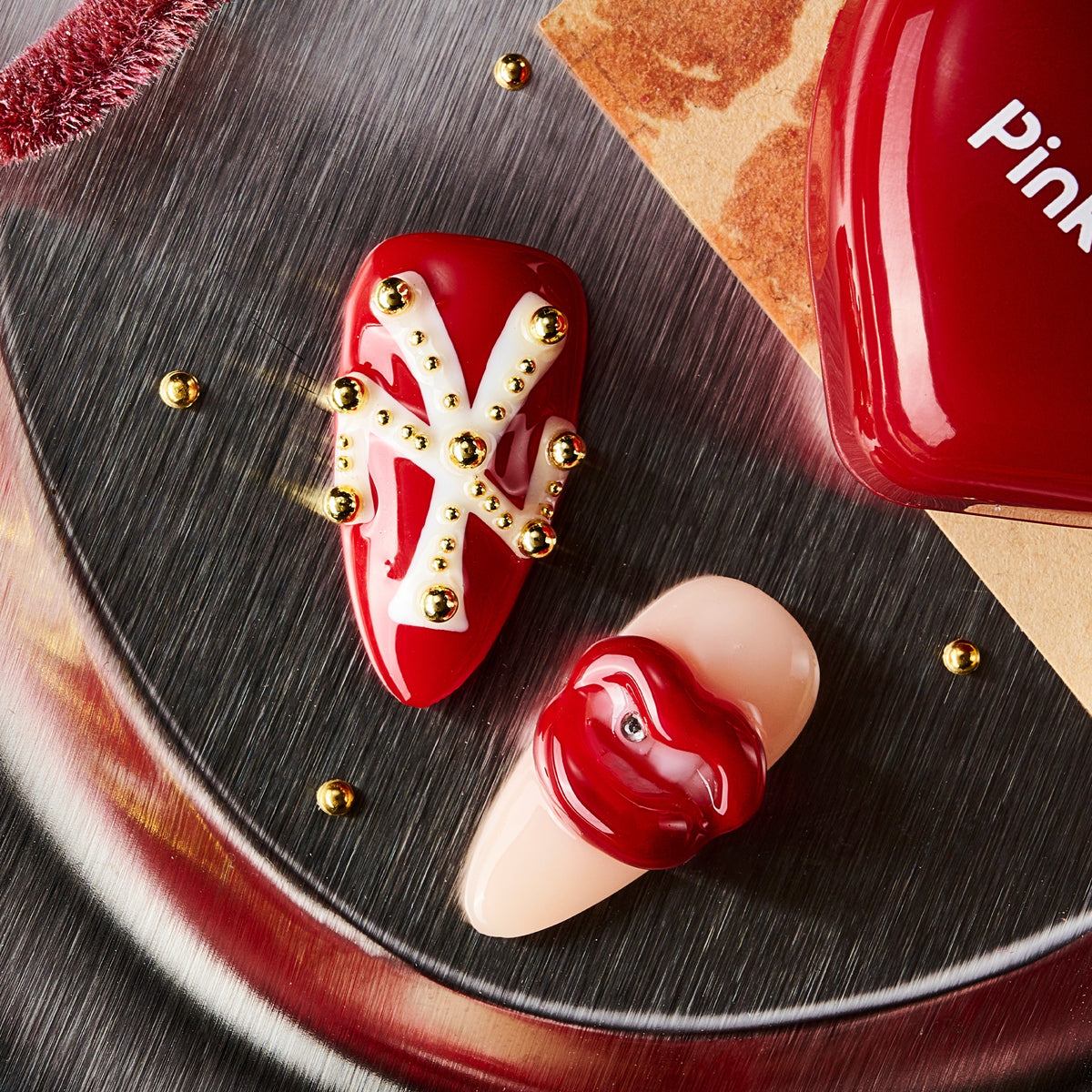 Artistic press on nails with sculpted red lips and studded details. Handmade reusable nail art set with bold style.
