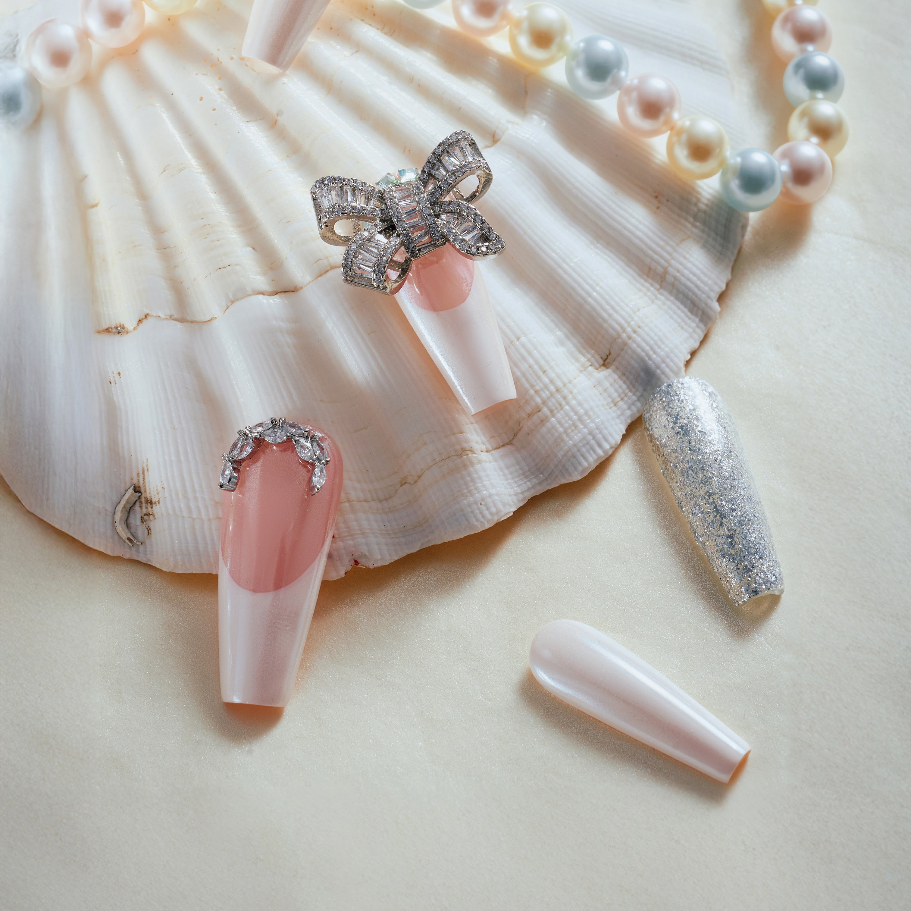 Pink and nude press on nails with silver glitter, rhinestones, and crystal bow charm