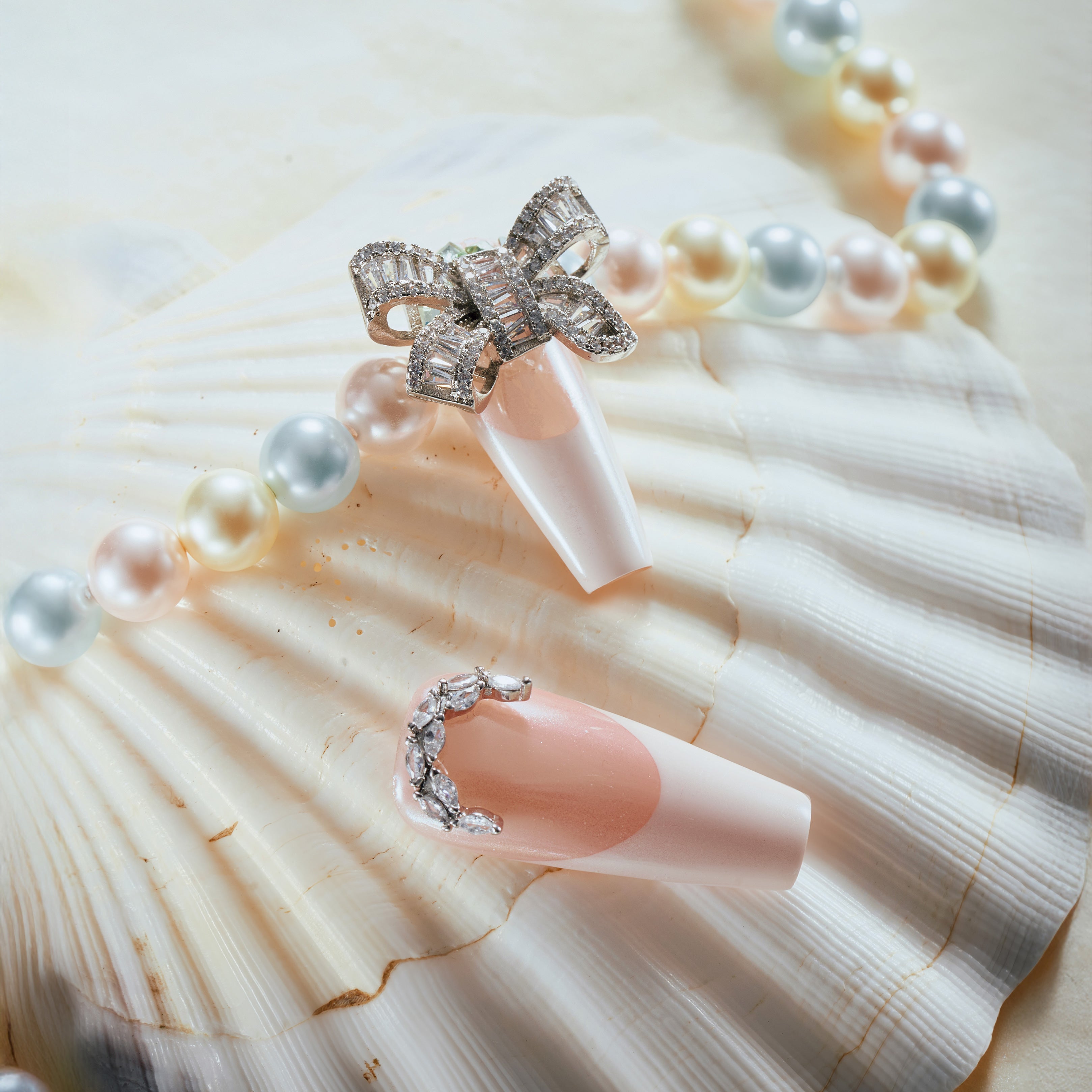 Pink and nude press on nails with silver glitter, rhinestones, and crystal bow charm