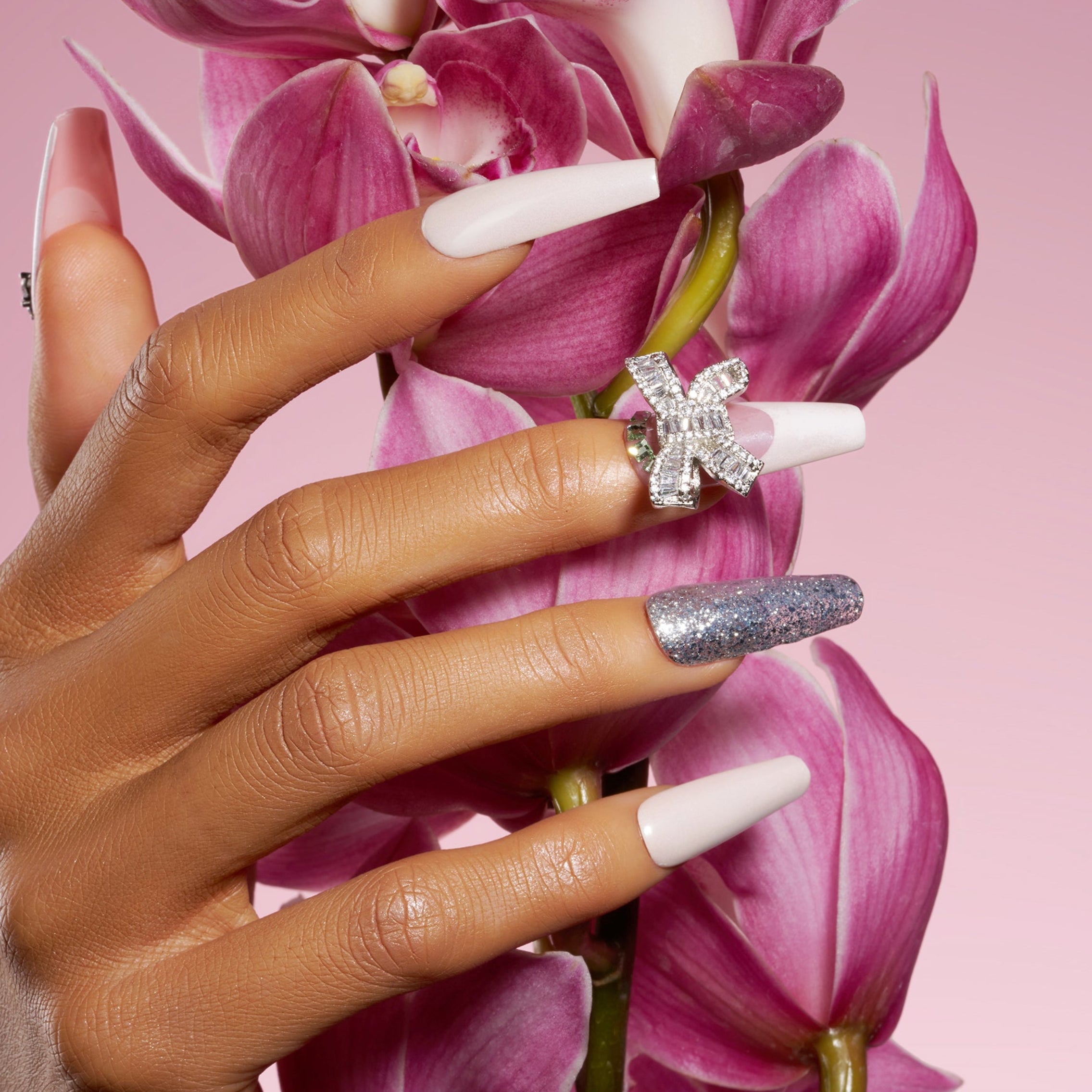 Pink and nude press on nails with silver glitter, rhinestones, and crystal bow charm